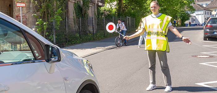 Schülerlotsin hält ein Auto an