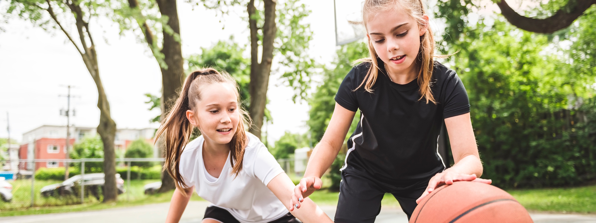 Zwei Mädchen in Sportkleidung spielen Basketball