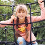 Mädchen sitzt auf einem Klettergerüst