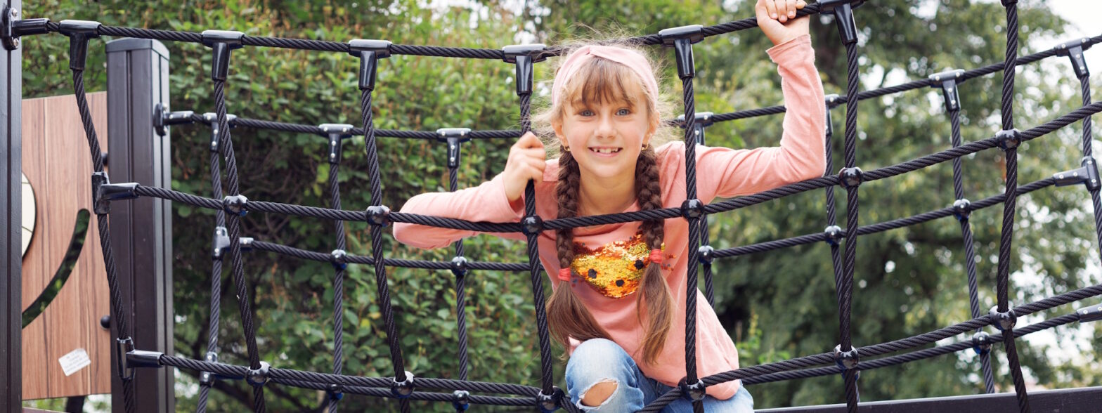 Mädchen sitzt auf einem Klettergerüst