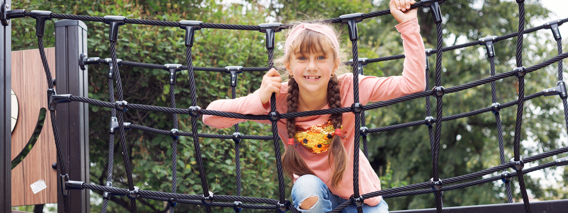 Mädchen sitzt auf einem Klettergerüst